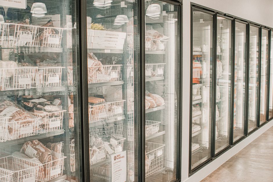 Een moderne wandkoeling in een drukke horecakeuken, gekoelde producten overzichtelijk en bereikbaar.